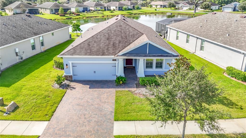 An aerial view of a suburban house with a paved driveway and a backyard pond — 5252 CAPPLEMAN LOOP, BROOKSVILLE, FL