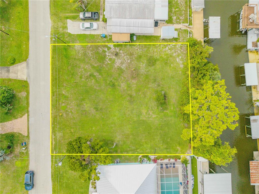 An aerial view shows a vacant, rectangular grassy lot situated between two residential properties — 113 CHARLES STREET, EDGEWATER, FL
