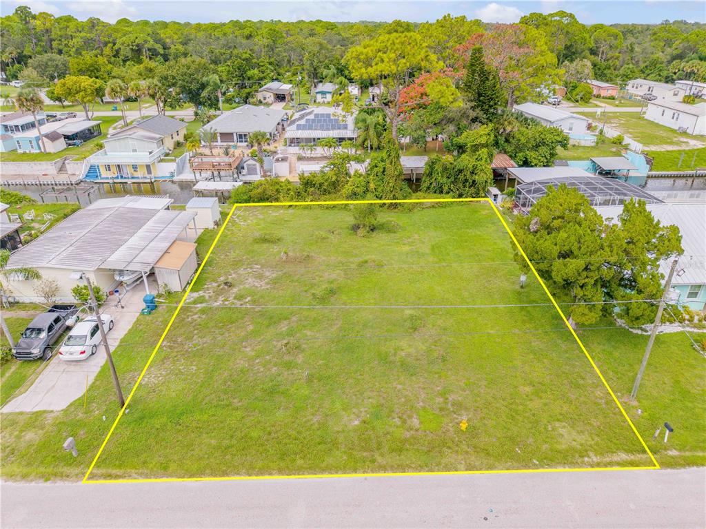 An aerial view shows a vacant, rectangular residential lot outlined in yellow along a road — 113 CHARLES STREET, EDGEWATER, FL