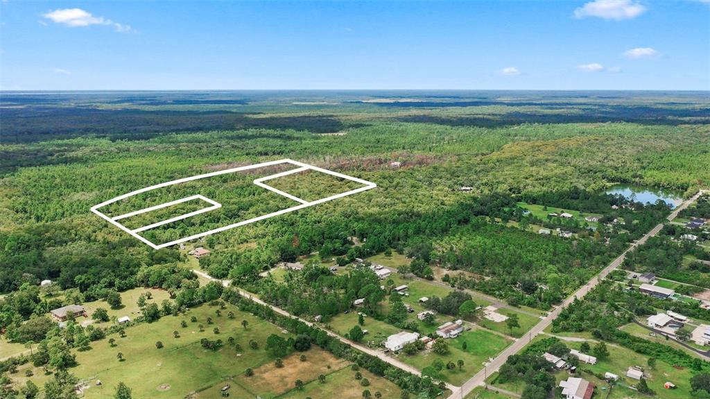 An aerial view shows a large, wooded plot of land outlined in white — UNKNOWN, MIMS, FL