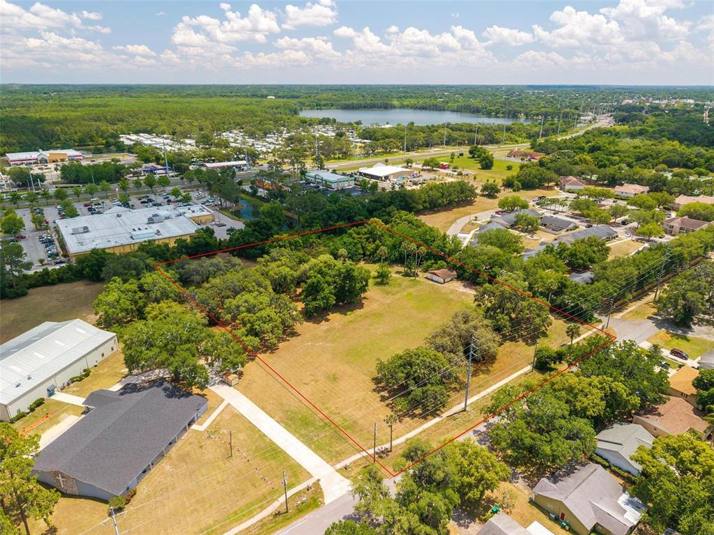 An aerial view shows a large, rectangular vacant lot outlined in red, surrounded by trees — 1925 COUNTY ROAD 19A, EUSTIS, FL