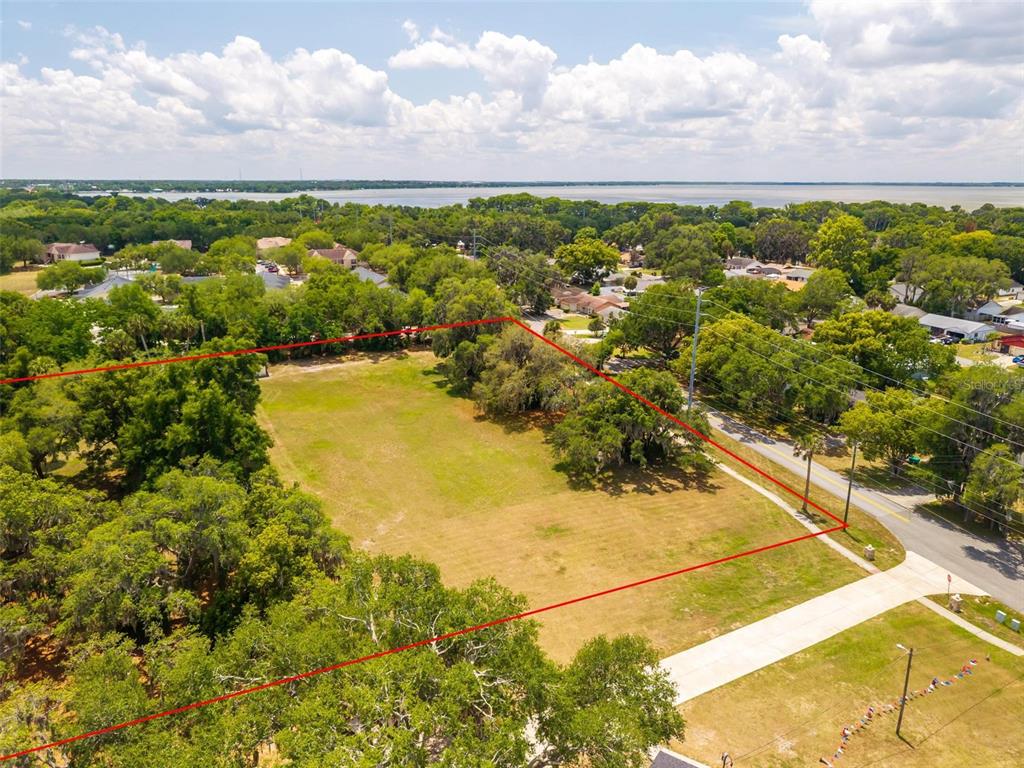 An aerial view shows a large, rectangular vacant lot outlined in red near a road — 1925 COUNTY ROAD 19A, EUSTIS, FL