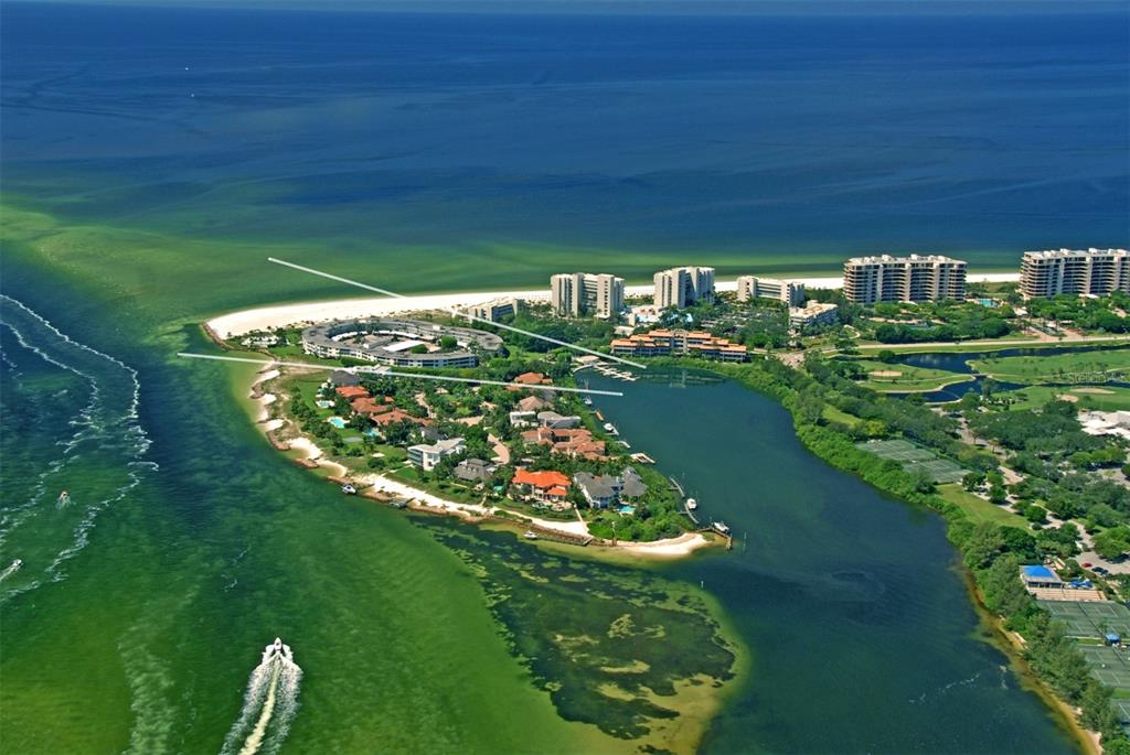 An aerial view shows a coastal residential community surrounded by water with a boat nearby — 100 SANDS POINT ROAD UNIT 324, LONGBOAT KEY, FL