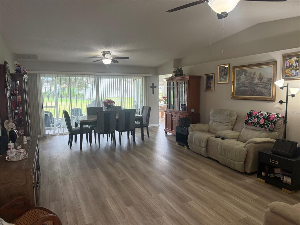A dining area and living room with wood-look flooring, a ceiling fan, and sliding glass doors — 2012 LONG BOAT DRIVE, LAKELAND, FL
