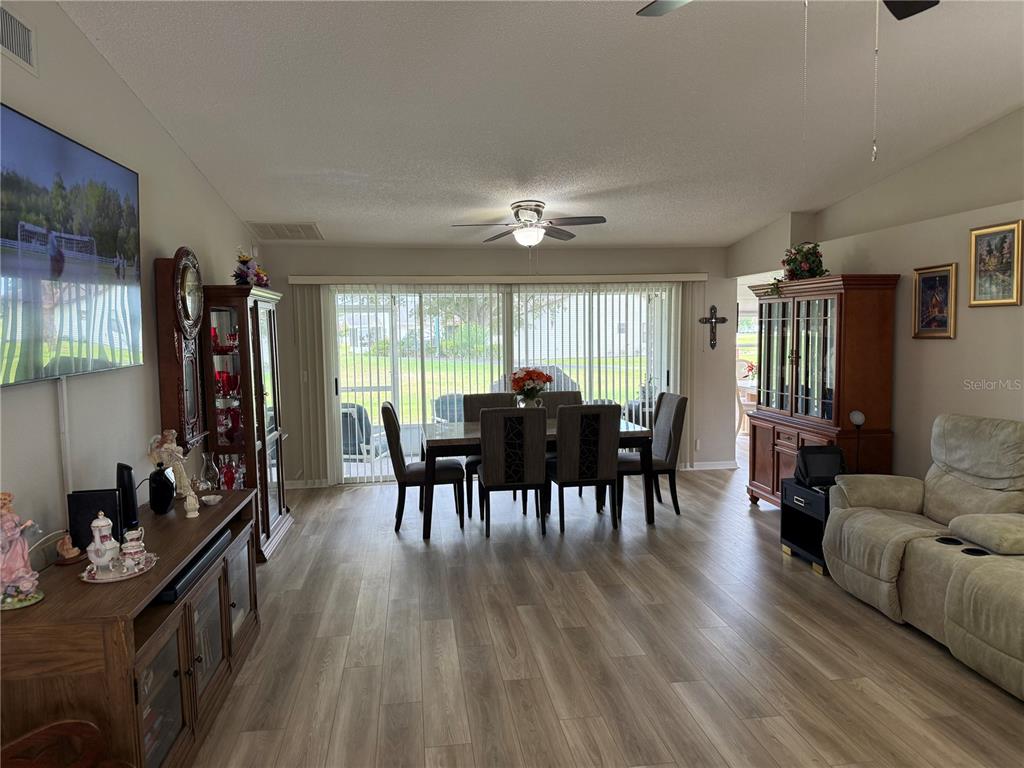 A living and dining area features wood-look flooring, a ceiling fan, and sliding glass doors — 2012 LONG BOAT DRIVE, LAKELAND, FL