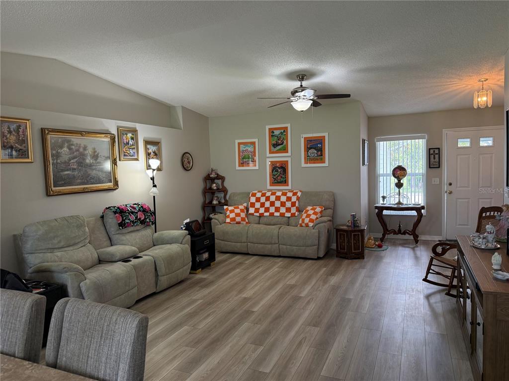 A living room features light-colored sofas, wood-look flooring, framed wall art, and a ceiling fan — 2012 LONG BOAT DRIVE, LAKELAND, FL