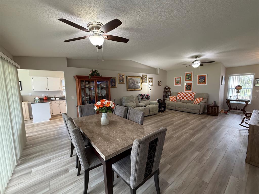 An open-concept dining and living area features wood-look flooring, two ceiling fans, and neutral walls — 2012 LONG BOAT DRIVE, LAKELAND, FL