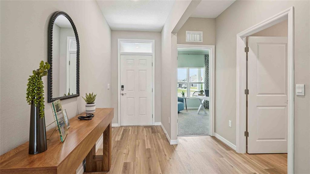 A bright entryway features wood-look flooring, a console table, a mirror, and a front door — 24234 NW 13TH BOULEVARD, NEWBERRY, FL