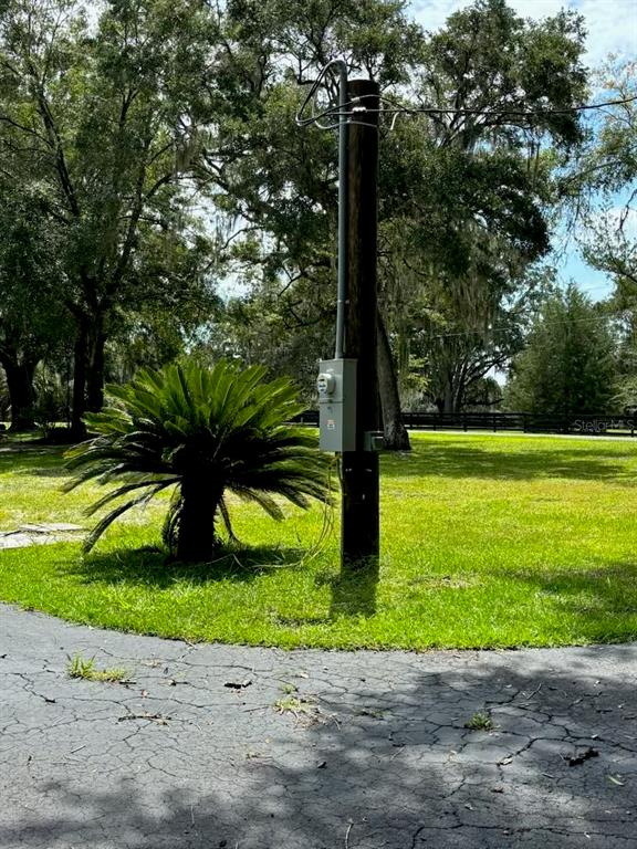 A utility pole with an electrical meter stands in a grassy yard near a driveway — 12125 NW 100TH STREET, OCALA, FL