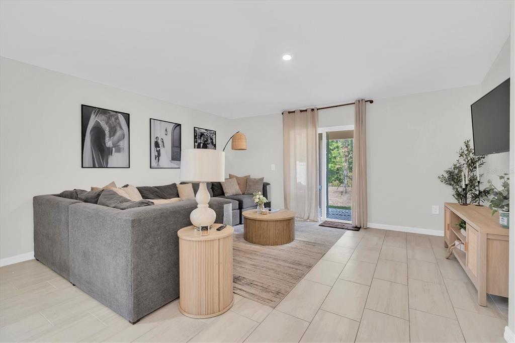 A living room features a gray sectional sofa, a round coffee table, and tile flooring — 10155 GENTLE RAIN DRIVE, LAND O LAKES, FL