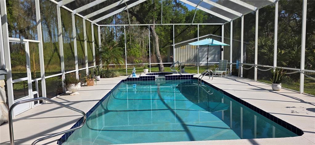A screened-in swimming pool and spa area with a patio and outdoor furniture — 10741 PINTO DRIVE, HUDSON, FL
