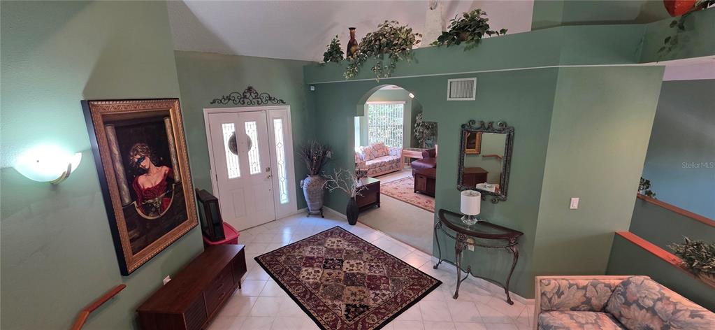 An entryway features a tiled floor, a patterned rug, and an arched opening to a living area — 10741 PINTO DRIVE, HUDSON, FL