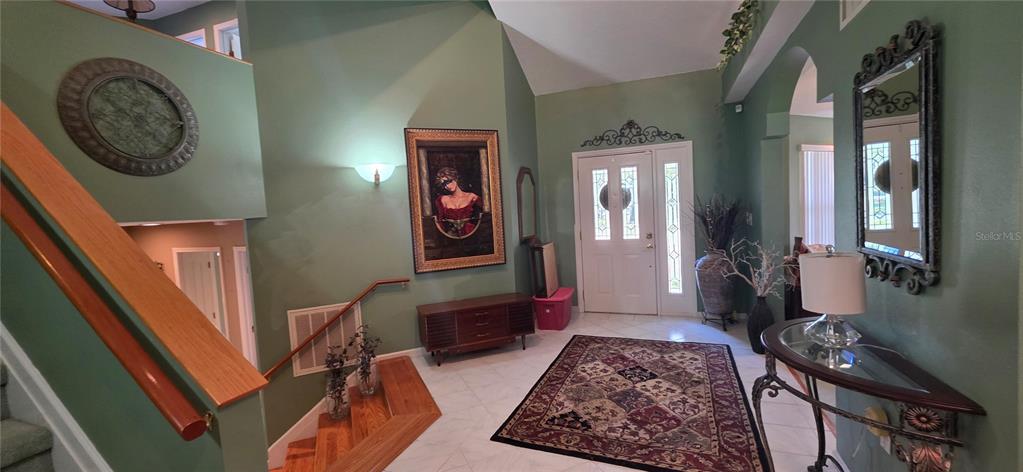 A foyer features a staircase, a patterned area rug, and a console table with a lamp — 10741 PINTO DRIVE, HUDSON, FL