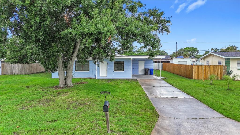 A light blue, single-story house with a concrete driveway and a large tree in front — 6228 FLORIDA CIRCLE W, APOLLO BEACH, FL