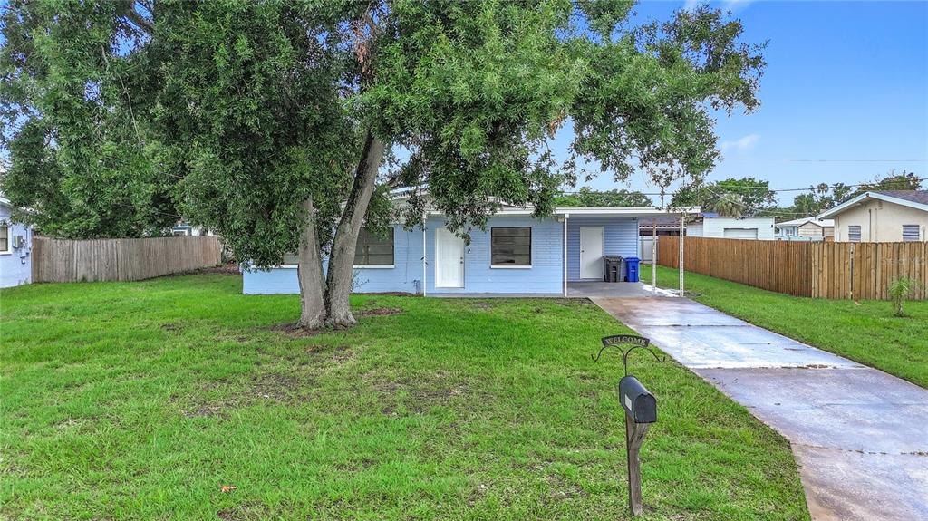 A light blue single-story house with a front lawn, a large tree, and a driveway — 6228 FLORIDA CIRCLE W, APOLLO BEACH, FL