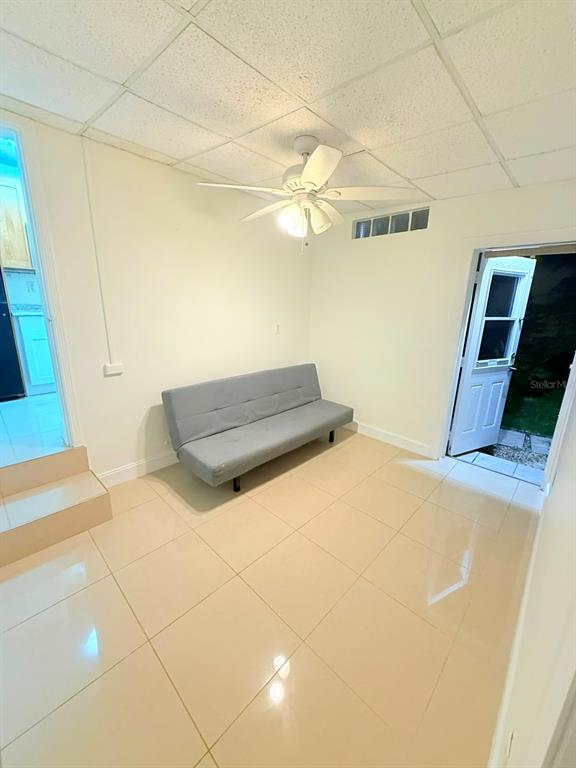 A room with light tile flooring, a gray futon, a ceiling fan, and an exterior door — 2300 SW 24TH STREET, MIAMI, FL