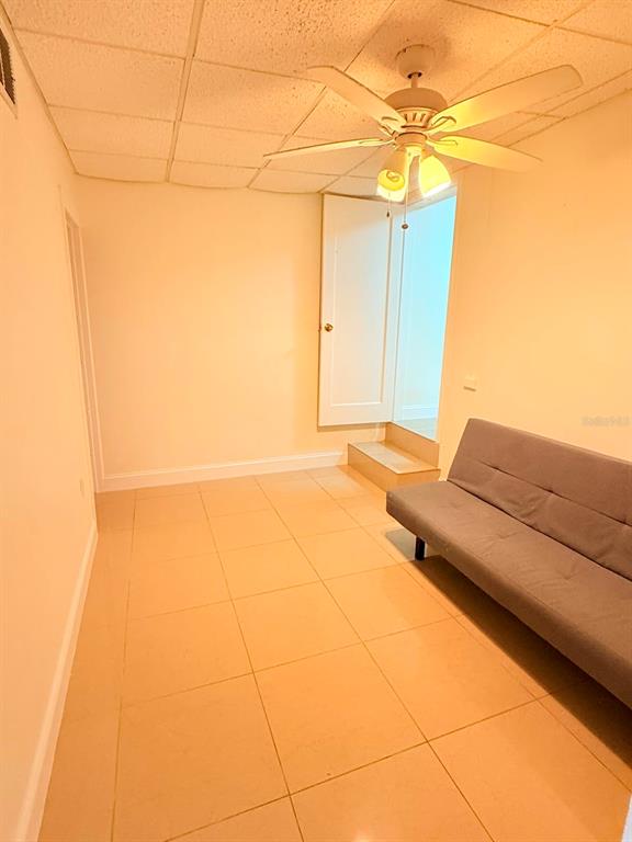 A room with light-colored tile flooring, a ceiling fan, and a gray futon sofa — 2300 SW 24TH STREET, MIAMI, FL