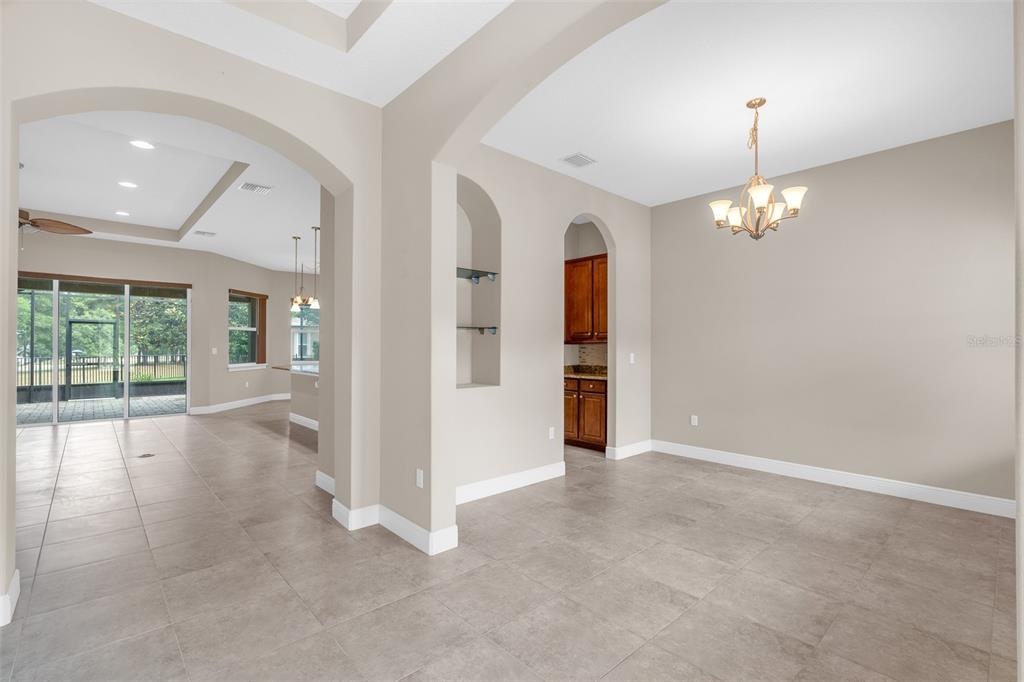 A dining room with a wooden table, six chairs, a chandelier, and two windows — 903 VICTORIA HILLS DRIVE S, DELAND, FL