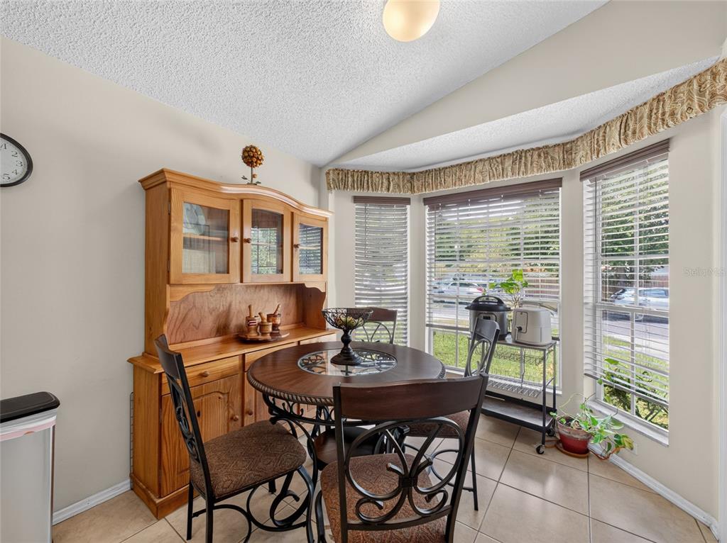 A dining area features a wooden hutch, a round table with chairs, and a bay window — 10225 CODY LANE, ORLANDO, FL