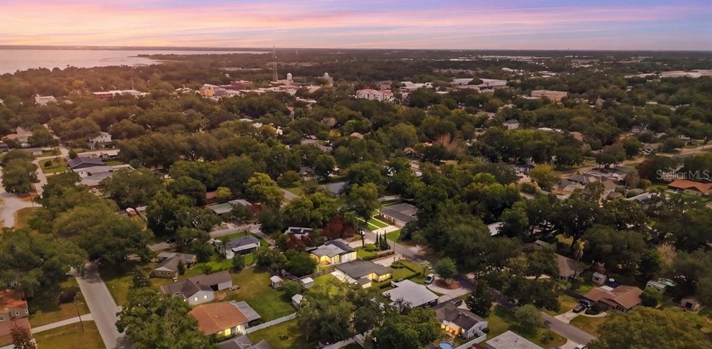 An aerial view shows a residential neighborhood with houses surrounded by trees near a coastline — 516 S HIGHLAND AVENUE, WINTER GARDEN, FL