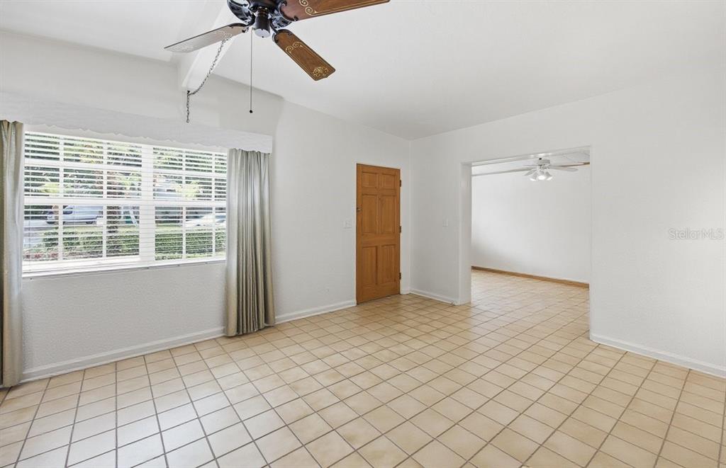 A room with white walls, tan tile flooring, a ceiling fan, and a wooden door — 516 S HIGHLAND AVENUE, WINTER GARDEN, FL