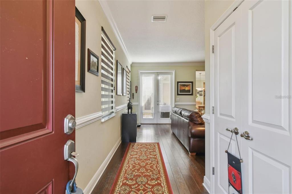 An entryway with hardwood floors, a red runner rug, and a view into the living room — 11329 RAVINIA PARK BOULEVARD, TAMPA, FL
