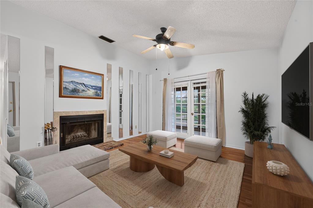 A living room features a fireplace, mirrored wall panels, a ceiling fan, and glass doors — 689 WELLINGTON STATION BOULEVARD UNIT 50, ORMOND BEACH, FL