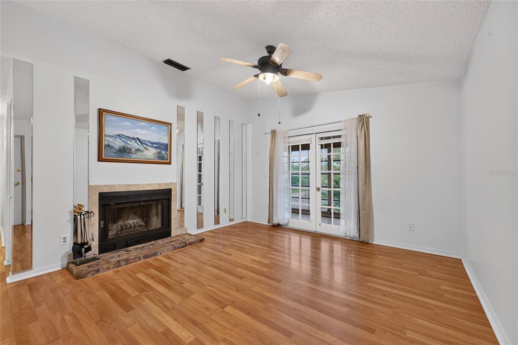 A living room features wood flooring, a fireplace with a brick hearth, and mirrored wall panels — 689 WELLINGTON STATION BOULEVARD UNIT 50, ORMOND BEACH, FL
