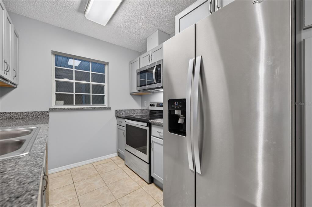 A kitchen with stainless steel appliances, grey cabinets, and granite countertops — 689 WELLINGTON STATION BOULEVARD UNIT 50, ORMOND BEACH, FL