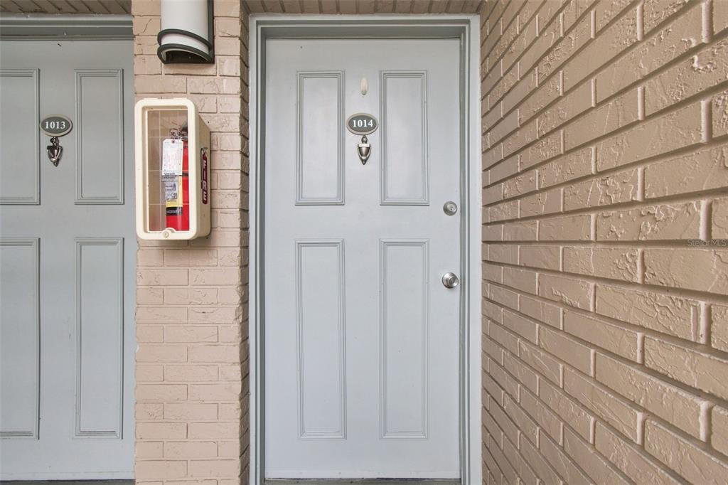 Two light gray apartment doors with unit numbers 1013 and 1014 set in a brick wall — 7210 N MANHATTAN AVENUE UNIT 1014, TAMPA, FL