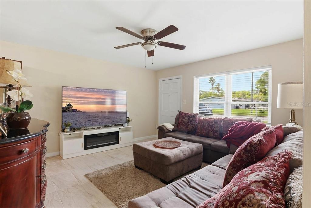A living room features a large sectional sofa, a television on a media console, and tile flooring — 4915 PINE NEEDLE DRIVE, ORLANDO, FL