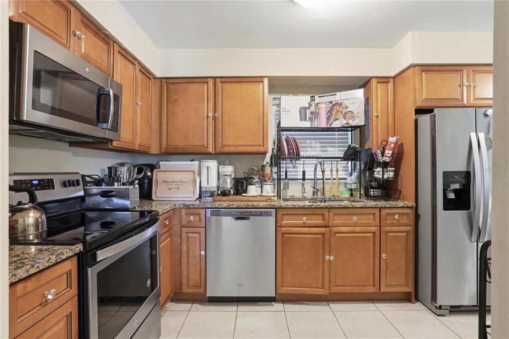 A kitchen features wood cabinets, stainless steel appliances, and granite countertops — 4915 PINE NEEDLE DRIVE, ORLANDO, FL