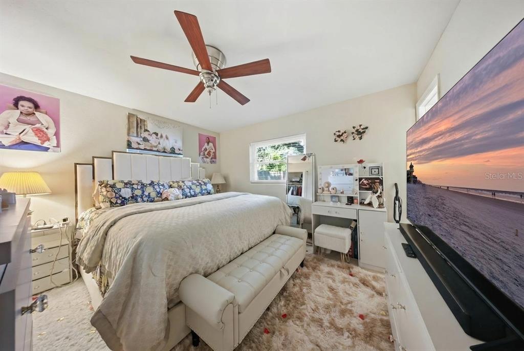 A bedroom features a large bed with a tufted headboard, a ceiling fan, and a television — 4915 PINE NEEDLE DRIVE, ORLANDO, FL