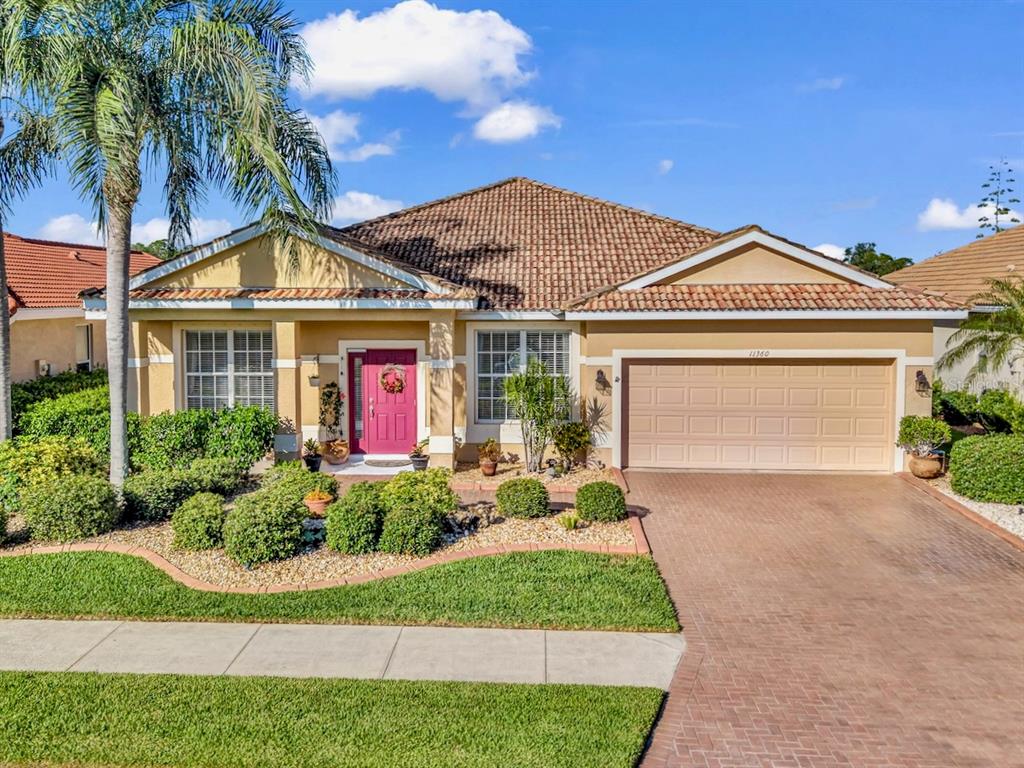 An aerial view of a suburban house with a tile roof, driveway, and waterfront backyard — 11360 DANCING RIVER DRIVE, VENICE, FL
