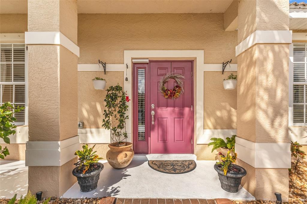 A front porch features a magenta door with a side light and potted plants — 11360 DANCING RIVER DRIVE, VENICE, FL