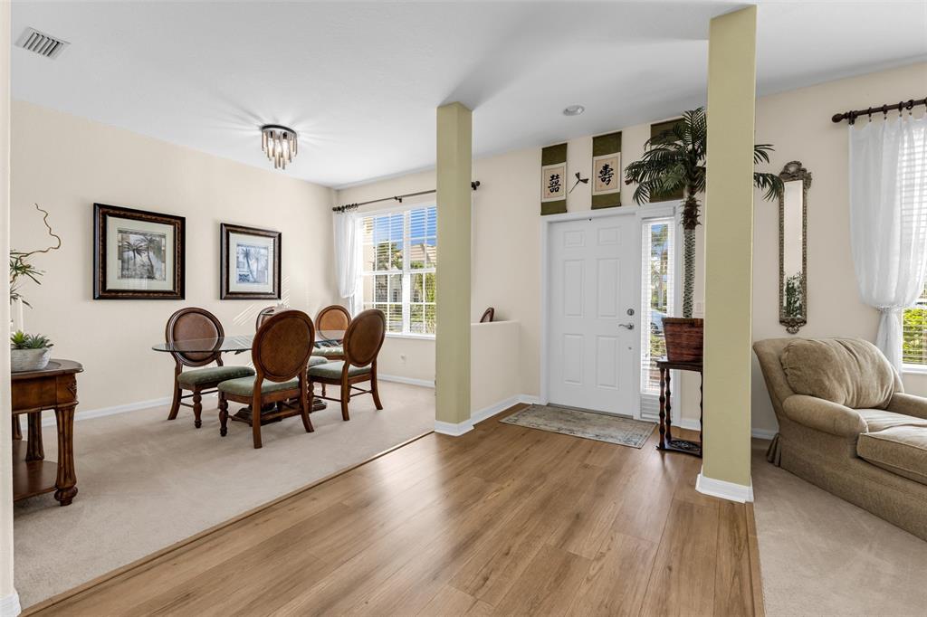 A dining area with carpeted floors sits adjacent to a wood-floored entryway and living room — 11360 DANCING RIVER DRIVE, VENICE, FL