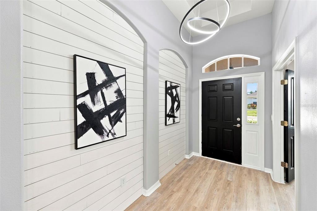An entryway features white shiplap accent walls, black abstract art, and a black front door — 1501 FLATWOOD COURT, TRINITY, FL