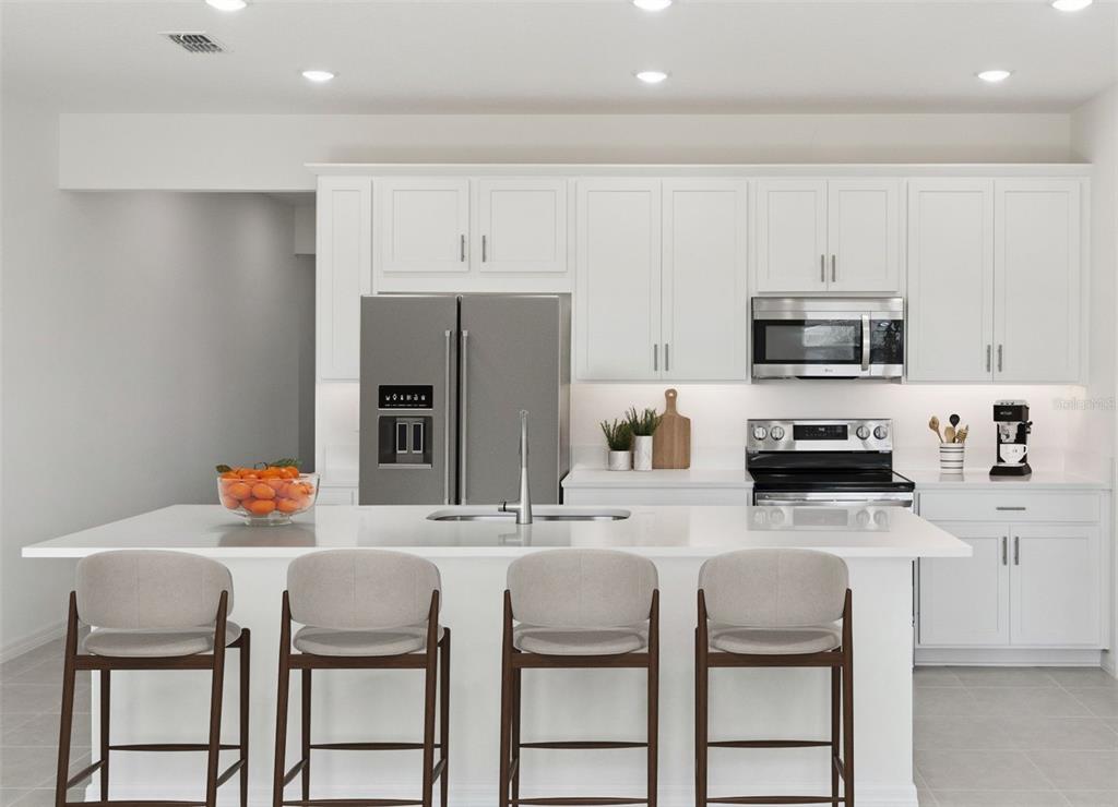 A modern kitchen features white cabinetry, stainless steel appliances, and a large island with seating — 4275 DARBY COURT, EUSTIS, FL
