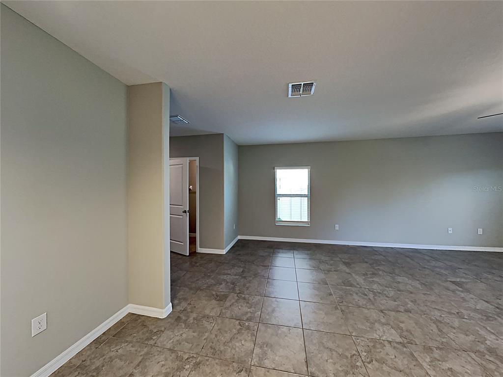 An empty room features light gray walls, large square floor tiles, and a single window — 5125 WHITE CHICORY DRIVE, RUSKIN, FL