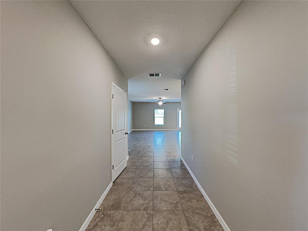 A tiled hallway leads into an open living area with a ceiling fan and window — 5125 WHITE CHICORY DRIVE, RUSKIN, FL