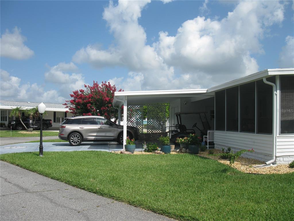 A mobile home exterior features a carport, a screened porch, and a paved driveway — 326 VICTORIA DRIVE, HAINES CITY, FL