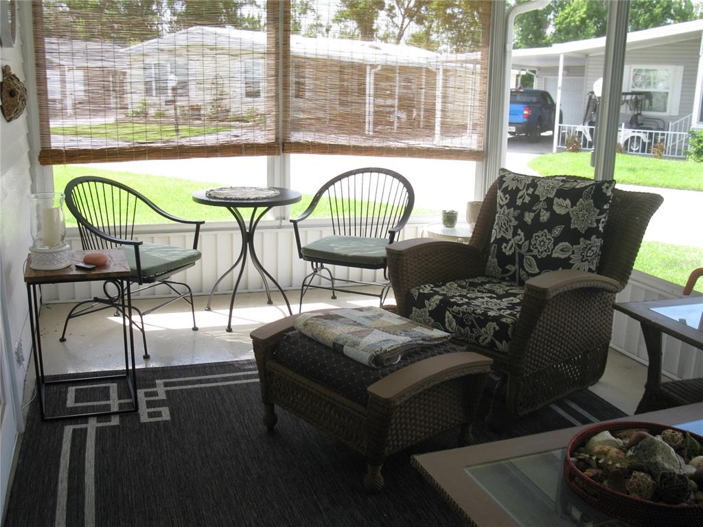 A sunroom features a wicker armchair with a matching ottoman, two metal chairs, and a table — 326 VICTORIA DRIVE, HAINES CITY, FL