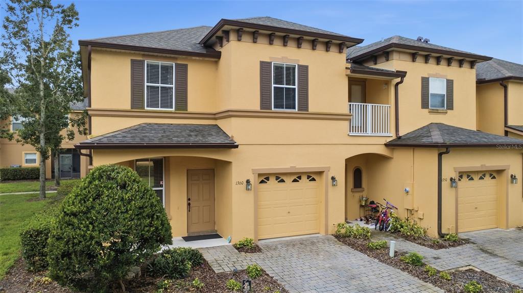A two-story tan townhouse with a paved driveway, a single-car garage, and a small balcony — 1360 LONG OAK WAY, SANFORD, FL