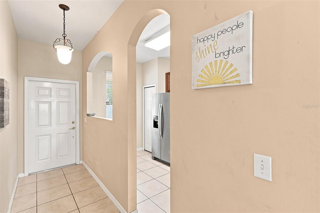 A tiled entryway features an arched doorway leading to a kitchen with a stainless refrigerator — 1360 LONG OAK WAY, SANFORD, FL