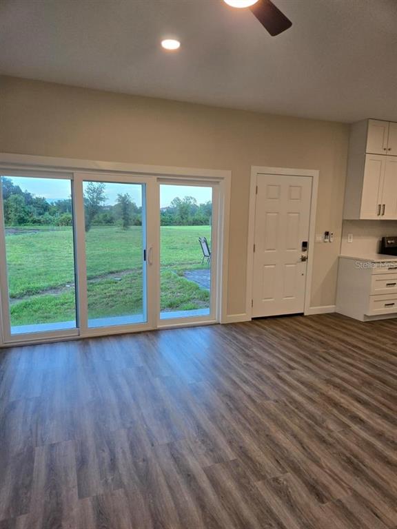 A room with wood-look flooring, sliding glass doors, a white door, and kitchen cabinetry — 1019 OAK BLUFF DRIVE, DAVENPORT, FL