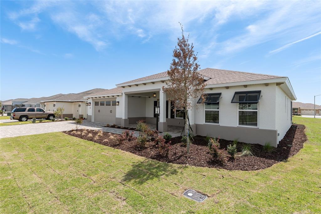 A single-story house with a tan stucco exterior, a covered front porch, and a driveway — 10154 SW 85TH PLACE ROAD, OCALA, FL