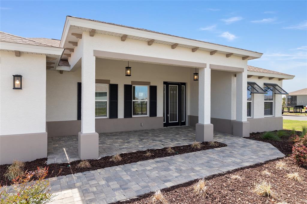 A covered front porch with stone pavers leads to the entrance of a stucco house — 10154 SW 85TH PLACE ROAD, OCALA, FL