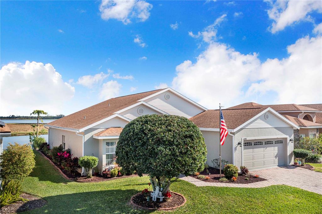 A single-story house with a tan exterior, a paved driveway, and a manicured front yard — 4081 DUNMORE DRIVE, LAKE WALES, FL