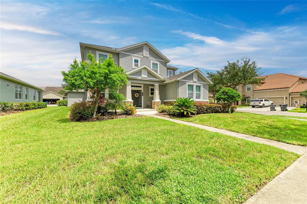 A two-story suburban house with gray siding, a stone base, and a green lawn — 20126 OUTPOST POINT DRIVE, TAMPA, FL