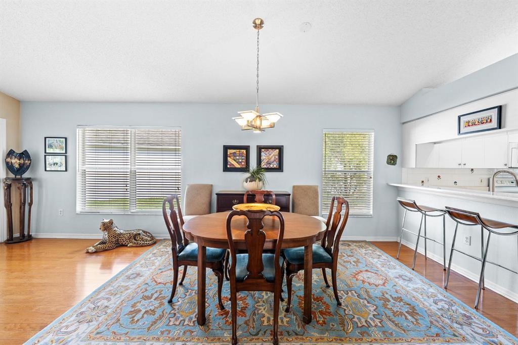 A dining room with a wooden table, chairs, area rug, and a breakfast bar — 1249 WINDING WILLOW DRIVE, TRINITY, FL